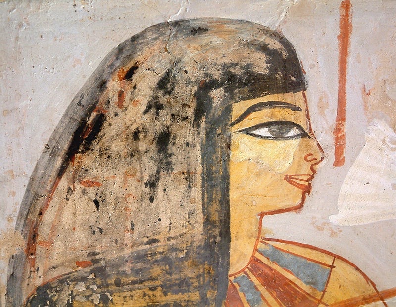 Ancient Egyptian wall painting depicting a woman in profile with dark hair and a large outlined eye, wearing a patterned garment against a pale background.